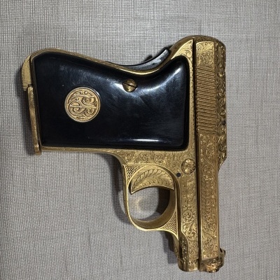 Pistola dourada decorada com punho negro e emblema circular dourado