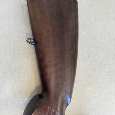 Coroanha de arma de caça em madeira castanha sobre tecido bege