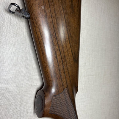 Coronha de rifle em madeira castanha com textura quadriculada e metal prateado