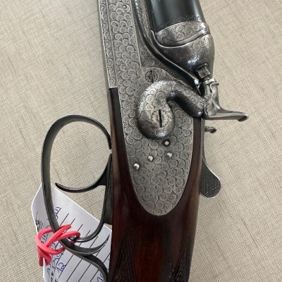 Espingarda dupla com madeira escura e metal gravado detalhadamente