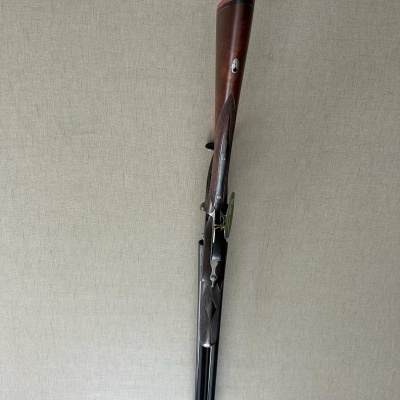 Espingarda de canos duplos com coronha em madeira escura encostada na parede