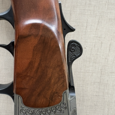 Punho e coronha de espingarda em madeira castanha com detalhes em metal gravado
