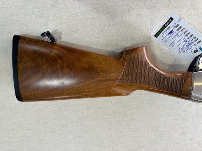 Coroa de espingarda em madeira castanha com textura e etiqueta ao lado