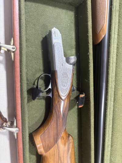 Espingarda de canos paralelos com madeira trabalhada e metal gravado numa caixa verde