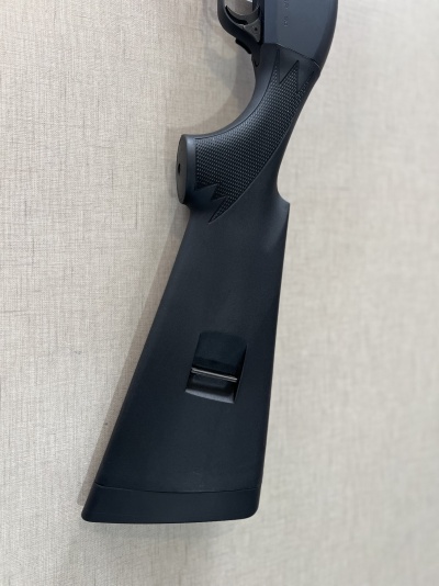 Coronha preta de espingarda com textura antiderrapante contra parede bege