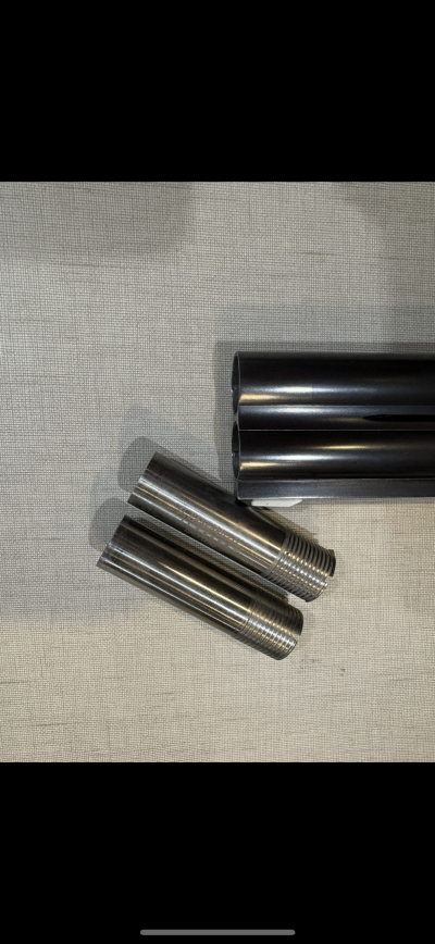 Peças cilíndricas metálicas com rosca e tubos pretos em tecido cinzento.