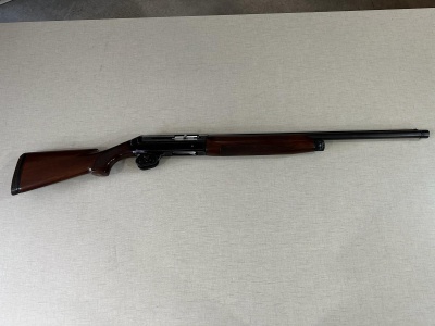 Espingarda de madeira castanha com cano preto sobre fundo cinza claro