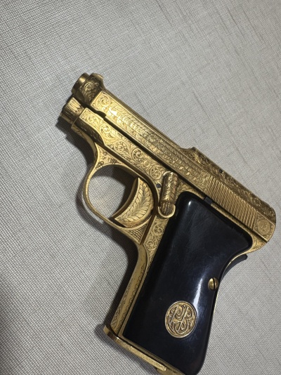 Pistola dourada com punho preto sobre tecido cinza