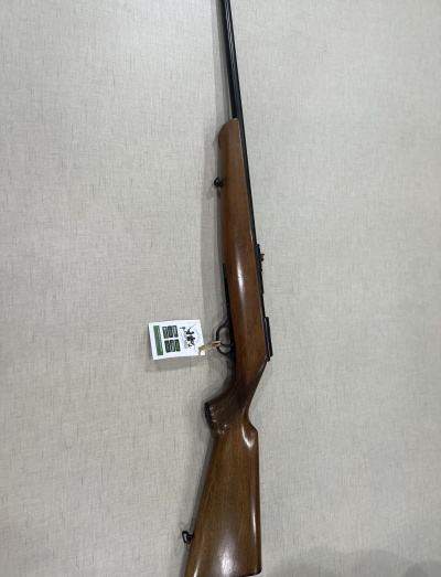 Carabina com coronha em madeira castanha e cano preto sobre superfície cinza