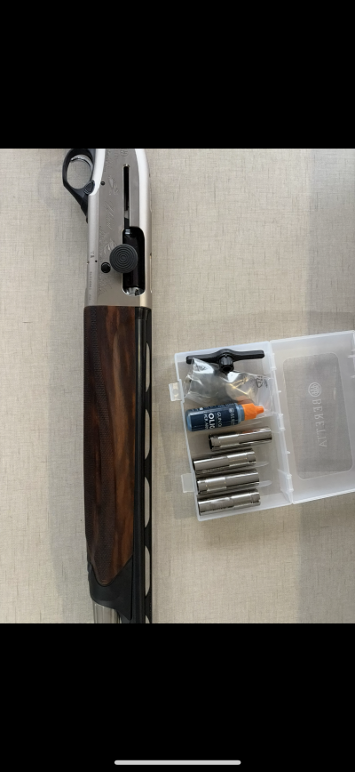 Espingarda com empunhadura em madeira e acessórios para manutenção numa caixa de plástico