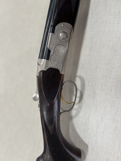Espingarda de caçador com corpo metálico gravado e coronha em madeira escura