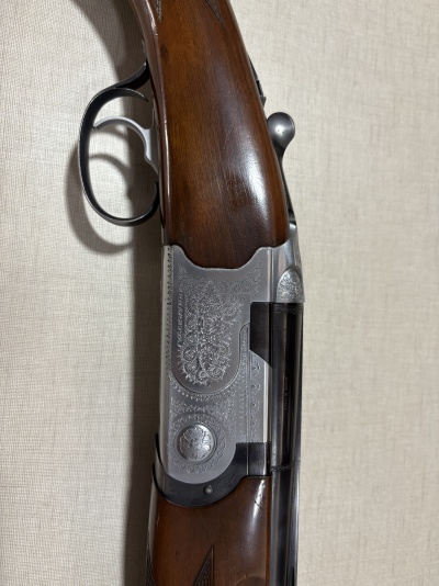 Espingarda com empunhadura de madeira e detalhes metálicos gravados