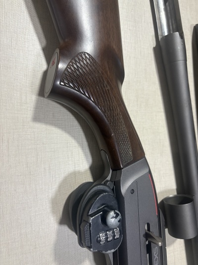 Parte de arma de fogo com empunhadura em madeira e cadeado numérico preto