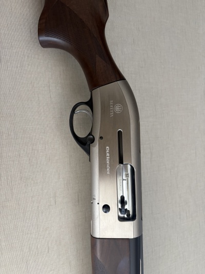 Espingarda Beretta Outlander com coronha em madeira castanha e corpo metálico prateado.