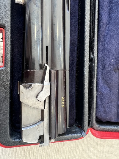 Arma de fogo cano duplo com inscrição MX8 dentro de estojo forrado a veludo azul escuro