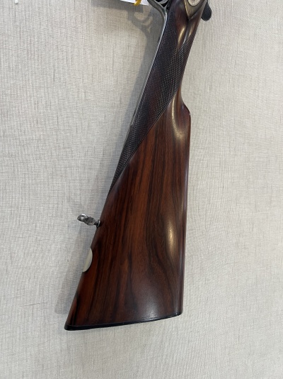 Coronha de madeira escura de espingarda com padrão xadrez e fundo cinzento