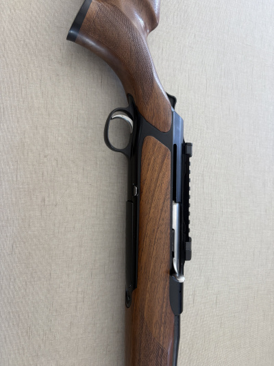 Detalhe de arma de fogo com madeira castanha e estrutura metálica preta