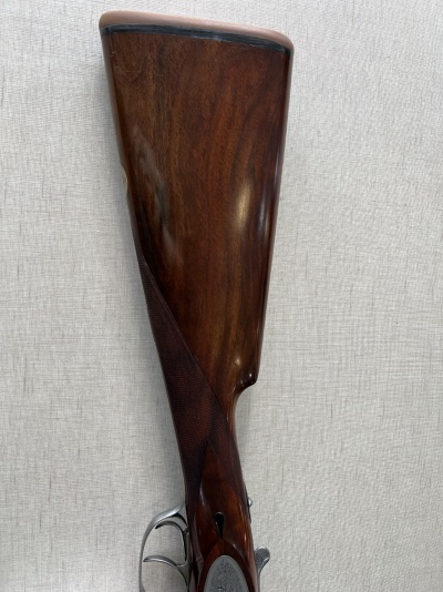 Coronha de espingarda em madeira escura polida com detalhes metálicos