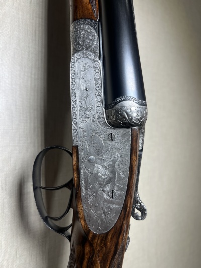Espingarda de canos duplos com madeira escura e acabamentos metálicos gravados