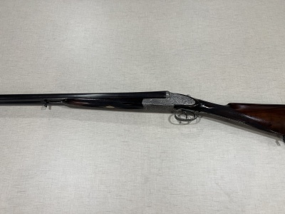 Espingarda de caça de cano duplo com cabo em madeira escura sobre tecido bege