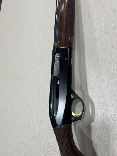 Espingarda de caça em madeira castanha e metal preto com fundo claro