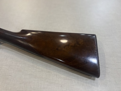 Puxador de arma em madeira polida castanha sobre superfície clara