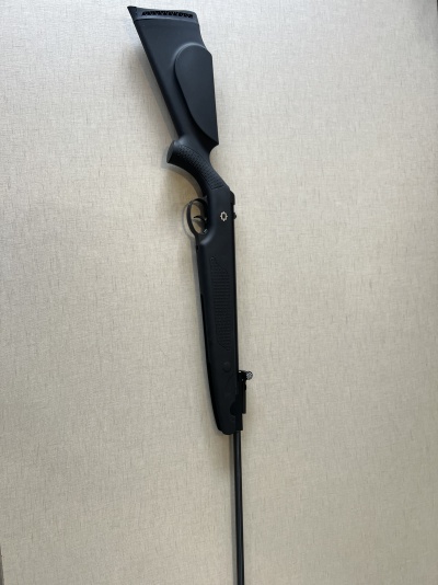 Espingarda preta com coronha e cano longo sobre fundo cinza