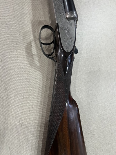 Espingarda de canos duplos com empunhadura de madeira escura e partes metálicas prateadas