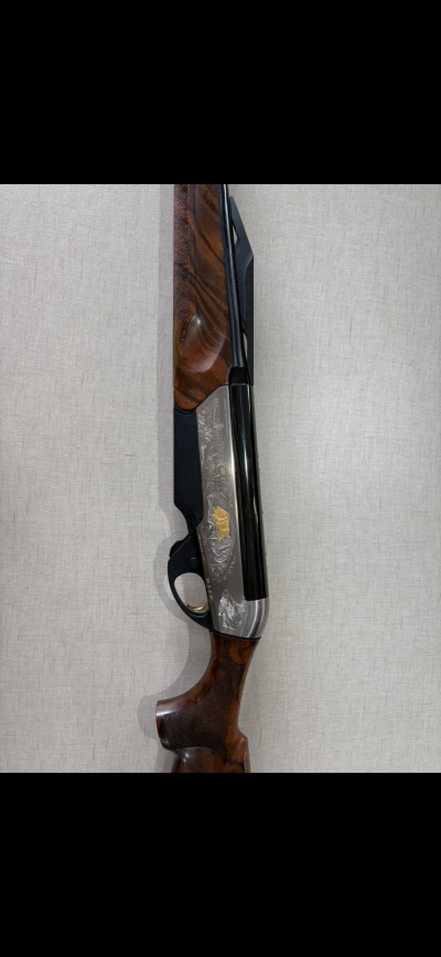 Espingarda com madeira castanha, metal prateado decorado e cano preto.