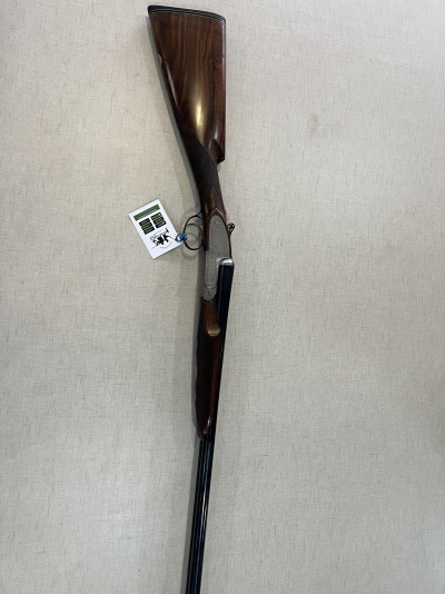 Espingarda de canos duplos com coronha em madeira escura e etiqueta pendurada