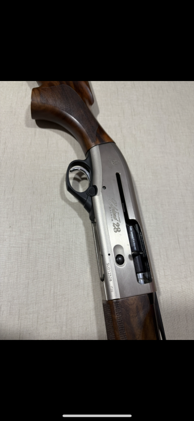 Partes de espingarda semiautomática em madeira castanha escura e metal cinza, com texto 'Beretta AL 391 URIKA 28 MAGNUM'