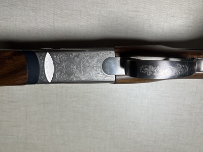 Espingarda com coronha de madeira escura e corpo metálico gravado