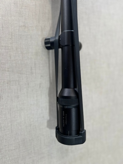 Mira telescópica preta montada numa arma com texto visível