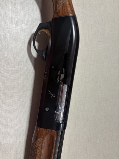 Espingarda com empunhadura em madeira e corpo preto com texto MONTEFELTRO e Benelli Inertia System