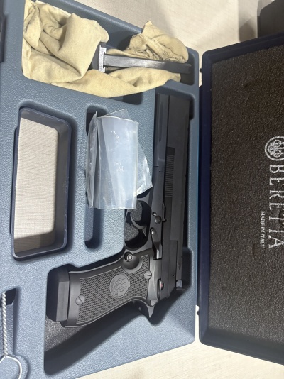 Pistola preta Beretta numa caixa azul com acessórios