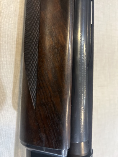 Parte de uma arma de fogo com madeira texturizada e metal gravado