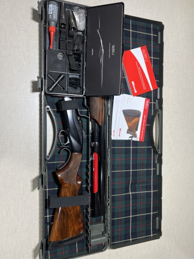 Estojo aberto com caçadeira desmontada, ferramentas e manuais