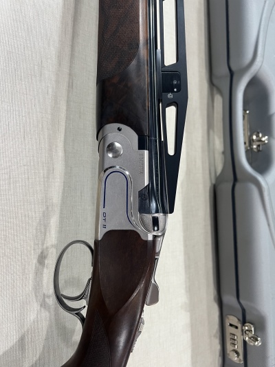 Espingarda de cano duplo com coronha em madeira escura e acabamento metálico prateado e preto