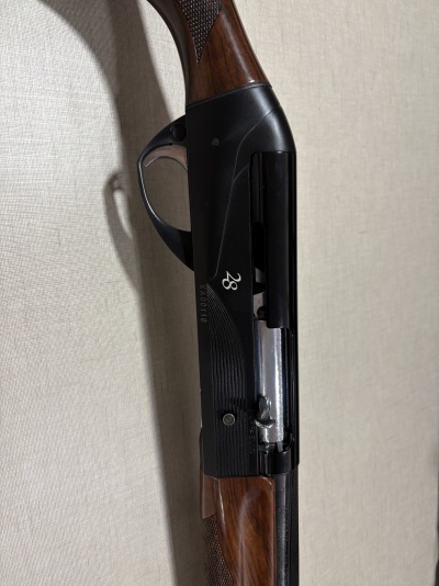 Espingarda de caça com corpo metálico preto e cabo em madeira castanha