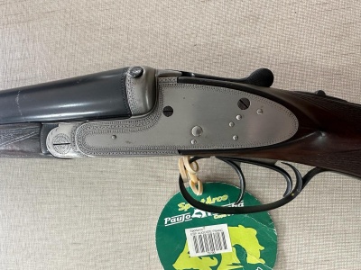 Espingarda de canos paralelos com coronha em madeira e etiqueta verde pendurada