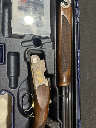 Espingarda de canos paralelos em estojo preto com detalhes em madeira e metal