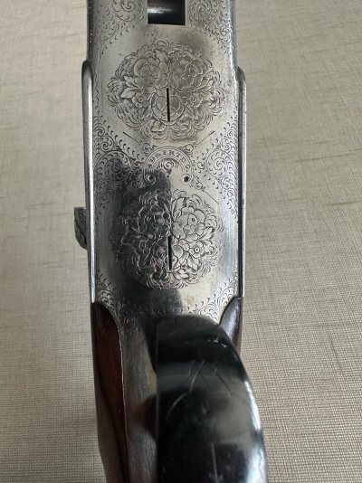 Mecanismo metálico gravado floral e punho de arma em madeira escura