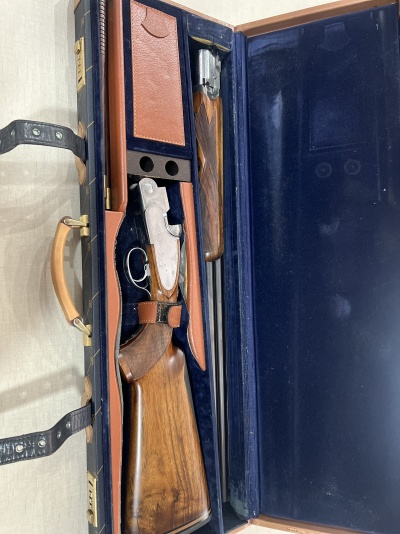 Mala azul com espingarda desmontada e compartimentos em couro castanho