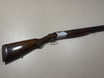 Espingarda de caça em madeira e metal sobre superfície cinzenta