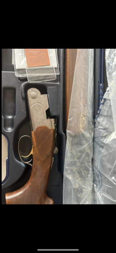 Arma de fogo Beretta com punho em madeira numa caixa preta com componentes embalados em plástico