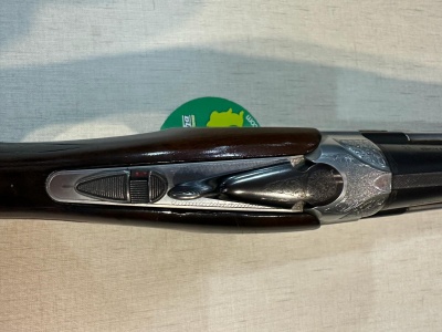 Espingarda de cano duplo com acabamento metálico e madeira escura sobre tecido branco