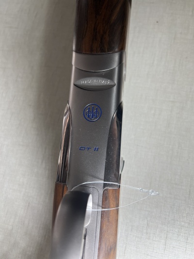 Parte central de espingarda em madeira e metal cinza com inscrições em azul