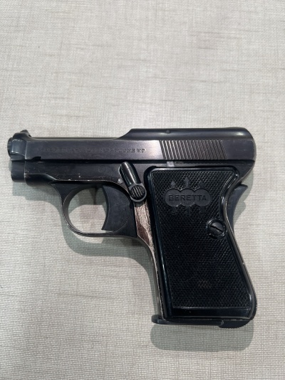 Pistola Beretta preta com empunhadura texturizada sobre tecido cinzento
