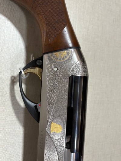 Região da empunhadura e caixa metálica com gravuras de uma arma de fogo