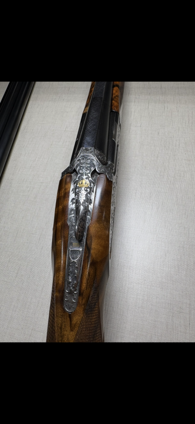 Espingarda de canos duplos com coronha de madeira e detalhes metálicos gravados